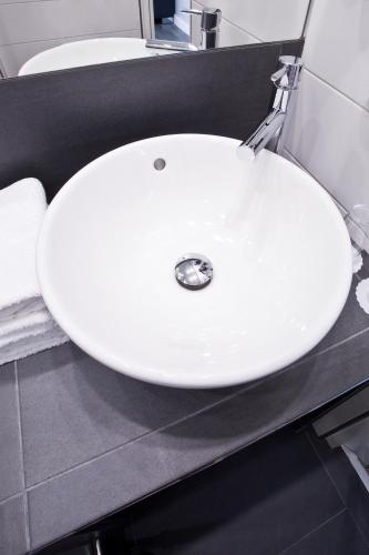 a white sink in a bathroom with a counter at PLAZA INN stays design Dortmund in Dortmund