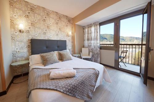 Un dormitorio con una cama grande y un balcón. en Hotel Sanchez, en Aínsa