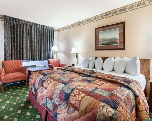 a hotel room with a large bed and chairs at Rodeway Inn Jasper in Jasper