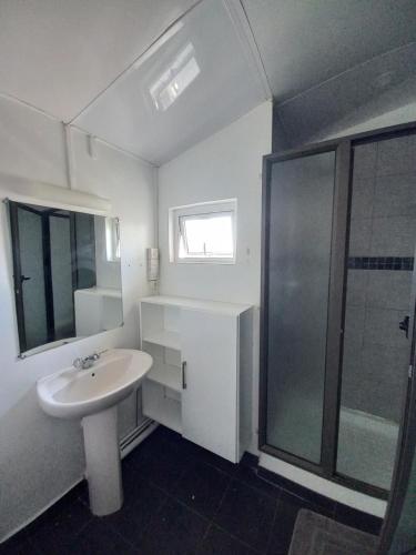 Un baño blanco con lavabo y ducha. en AVA BEACH HOUSE, en Blue Bay