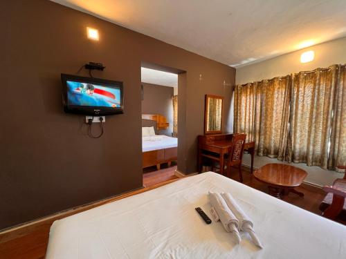 a room with a tv on the wall and a bed at Hotel Jc Grand in Kodaikānāl