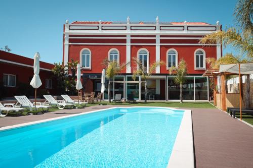 a swimming pool in front of a red building at Salmanha Residence in Figueira da Foz