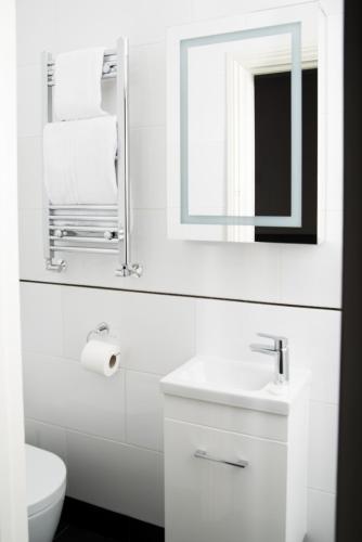 a white bathroom with a sink and a mirror at Hotel 63 in London