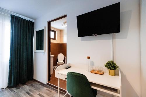 Habitación con escritorio y TV en la pared. en PENSIUNEA HAI IN MARAMURES en Bîrsana