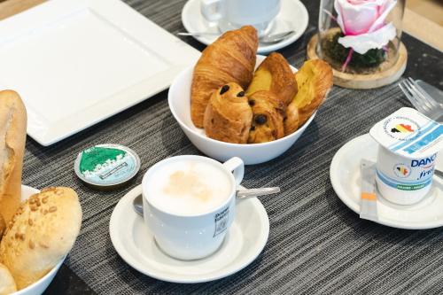 un tavolo con tazze di caffè e una ciotola di pane di Hotel Chambord a Bruxelles