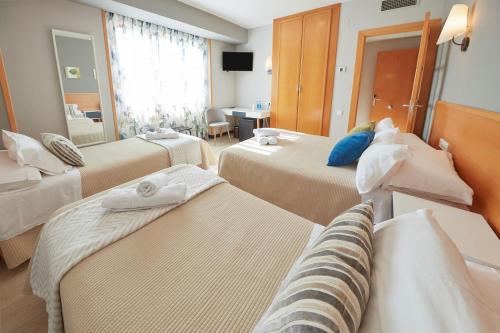 a hotel room with two beds and a mirror at Hotel Sanchez in Aínsa