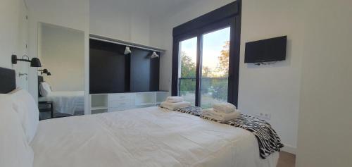 biała sypialnia z dużym łóżkiem i dużym oknem w obiekcie RICARDO APARTAMENTo w mieście San Jose de la Rinconada