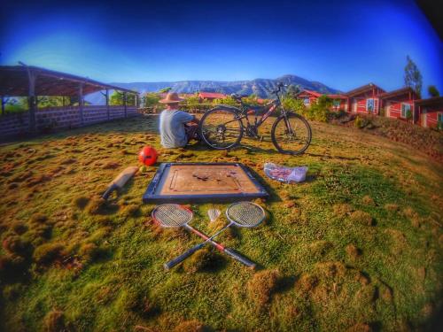 a man sitting in the grass with a table with tennis rackets at Mysticstays Resort in Wai