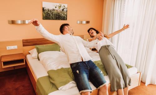 a man and a woman jumping on a bed at Weingut Kollerhof am Eichberg in Leutschach
