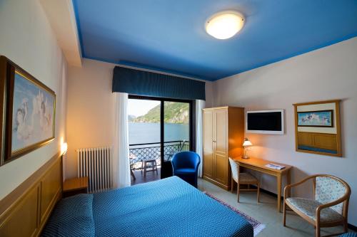 a hotel room with a bed and a desk and a window at Hotel Europa in Porlezza