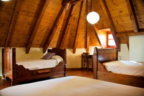 two beds in a room with wooden ceilings at Casa Helipa in Arró
