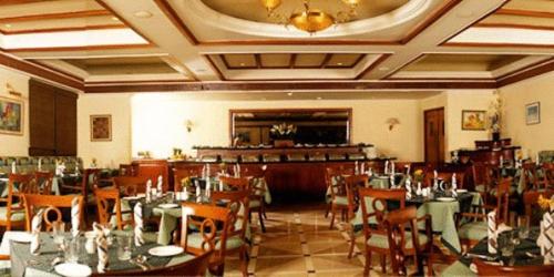a restaurant with tables and chairs in a room at Beverly Hotel in Chennai