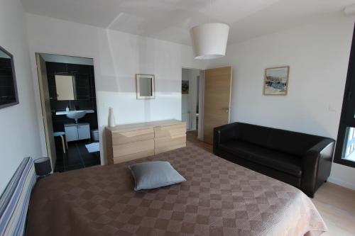 a bedroom with a bed and a black couch at Le Normandy in Pourville-sur-Mer
