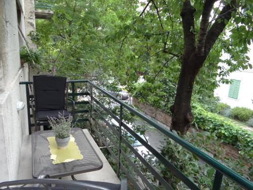 a balcony with a table and a chair and a tree at Rooms Stella in Split