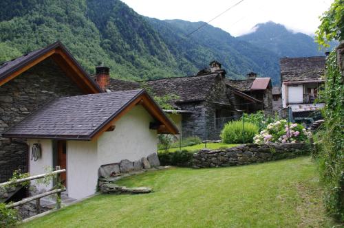 a small house with a grass yard in a village at Erebia Appartamenti Vacanza in Villadossola