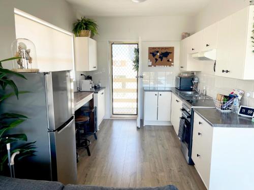 a kitchen with white cabinets and a stainless steel refrigerator at Seabreeze at Semaphore #8 - On the Esplanade in Semaphore