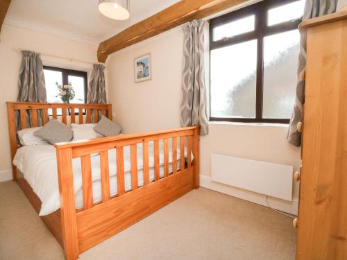 a bedroom with a crib and a window at Barn Cottage in Bude