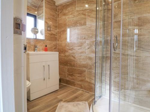 a bathroom with a shower with a toilet and a sink at Barn Cottage in Bude