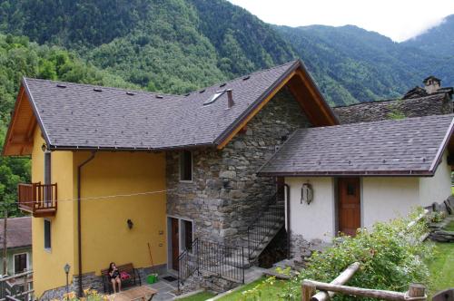 a stone house with a roof with mountains in the background at Erebia Appartamenti Vacanza in Villadossola