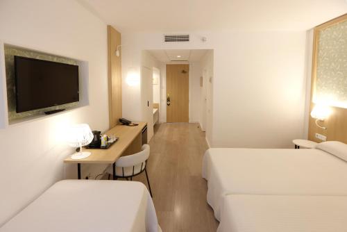a hotel room with two beds and a desk at Sercotel Carlos III in Cartagena