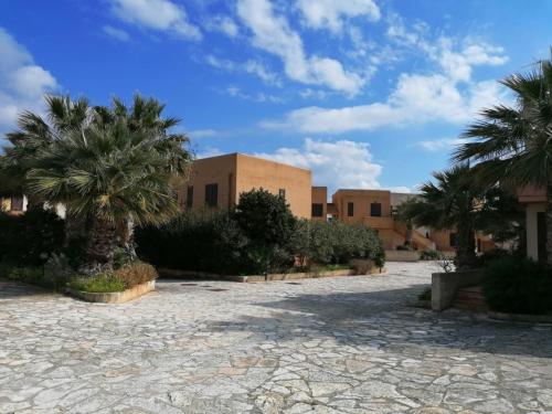 a building with palm trees in front of it at Kalea Casa Vacanze in Favignana