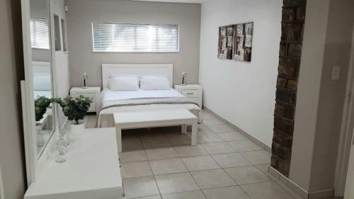 a white bedroom with a bed and a window at Feather Self Catering Accommodation in Windhoek
