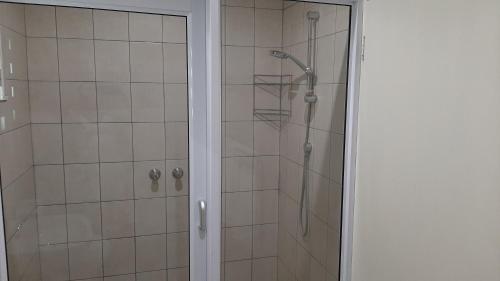 a shower with a glass door next to a shower at Feather Self Catering Accommodation in Windhoek