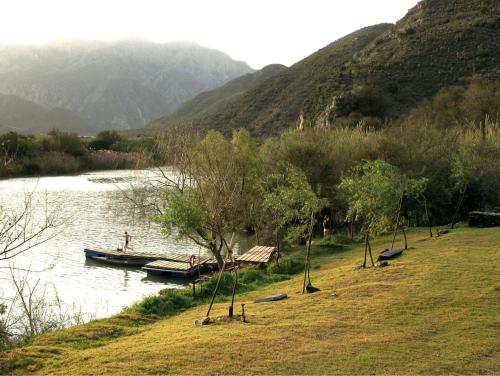 a boat is docked on a river with mountains at The Old School House in Calitzdorp