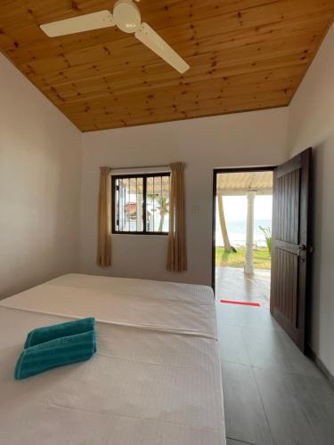 1 dormitorio con 1 cama blanca grande y ventana en Saman Beach Guest House en Galle