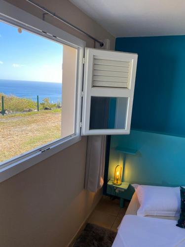 a bedroom with a window with a view of the ocean at Locations Morne aux Vents in Fond Boucher