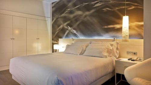 um quarto com uma cama branca e uma pintura na parede em NH Collection Villa de Bilbao em Bilbao