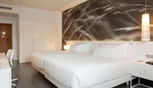 - une chambre avec un grand lit blanc orné d'une peinture murale dans l'établissement NH Collection Villa de Bilbao, à Bilbao