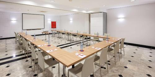 a conference room with long tables and chairs and a screen at NH Collection Villa de Bilbao in Bilbao