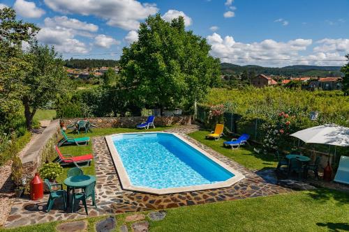 una piscina en un patio con sillas y mesas en Quintal De Alem Do Ribeiro-Turismo Rural en Lousã