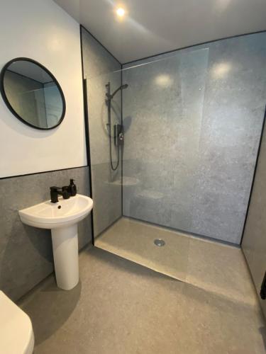 een badkamer met een douche, een wastafel en een spiegel bij Ormes Hey Apartments in Llandudno