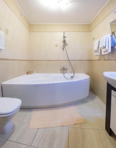 a bathroom with a tub and a toilet and a sink at Галицька Корона in Lviv
