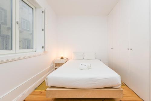 a white bedroom with a bed and a window at GuestReady - Triple C's in Porto