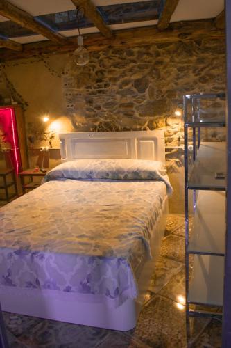 una camera da letto con un letto bianco in un muro di pietra di Casa en zona medieval a Monforte de Lemos