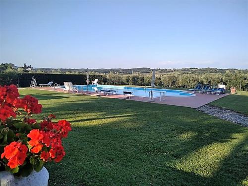 a large yard with a swimming pool and red flowers at I Girasoli di Lari - Appartamento Indipendente 2 camere da letto in Ripoli