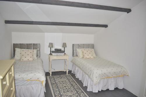 a bedroom with two beds and a table with a lamp at Gite Les Justices in Édon