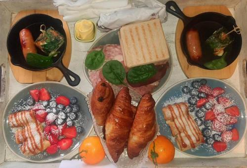 une table recouverte de assiettes de nourriture avec de la viande et des fruits dans l'établissement Golden Lion, à Bouillon