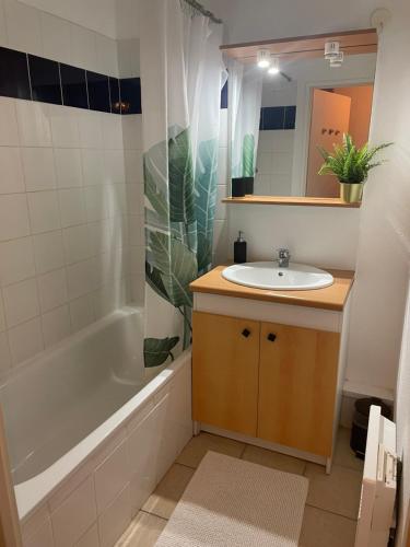 a bathroom with a sink and a tub and a mirror at Appartement T2 avec balcon, lumineux, au calme. in Blaye