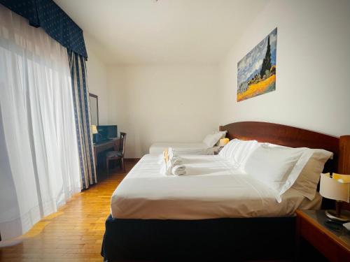 a bedroom with a large bed with white sheets at Hotel Hermitage in Poggio a Caiano