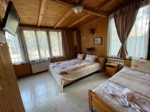 1 dormitorio con 2 camas, TV y ventanas en Вила Мерджан, en Sarnitsa