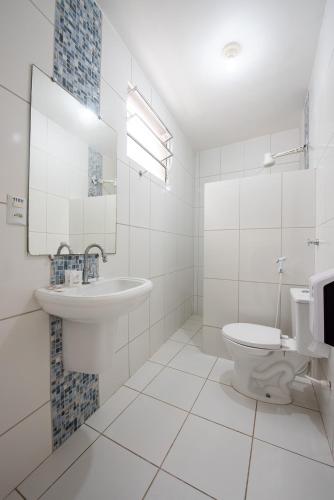 a white bathroom with a sink and a toilet at Hotel Prainha in Vila Velha