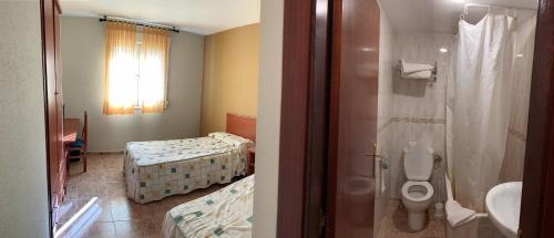 a bathroom with a toilet and a bathroom with two beds at Área 99 in Estella