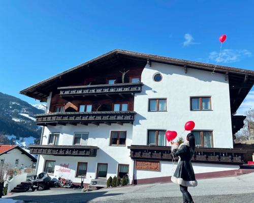 a woman holding two red balloons in front of a building at Hotel Marienhof in Fliess