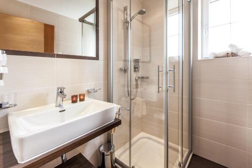 La salle de bains est pourvue d'un lavabo et d'une douche. dans l'établissement Apart Berghof, à Fiss