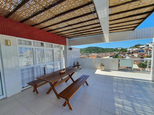 un patio avec une table et un banc en bois sur le toit dans l'établissement Cobertura 3 Suítes - Praia Grande - Arraial do Cabo, à Arraial do Cabo