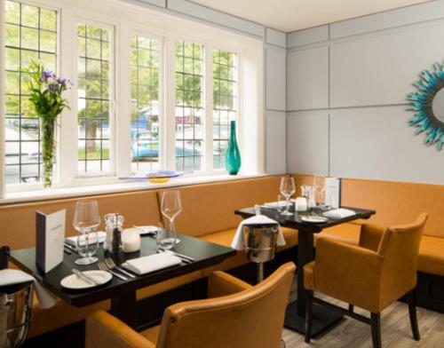 un restaurante con 2 mesas, sillas y ventanas en The Inn at Woodhall Spa en Woodhall Spa